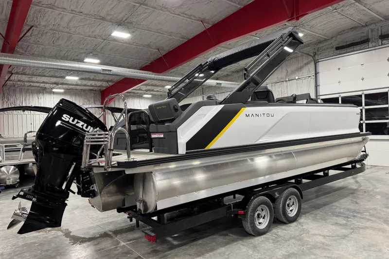 Slide: The Image of 2025 Manitou 24 Explore pontoon boat with Suzuki engine in a showroom. - 4