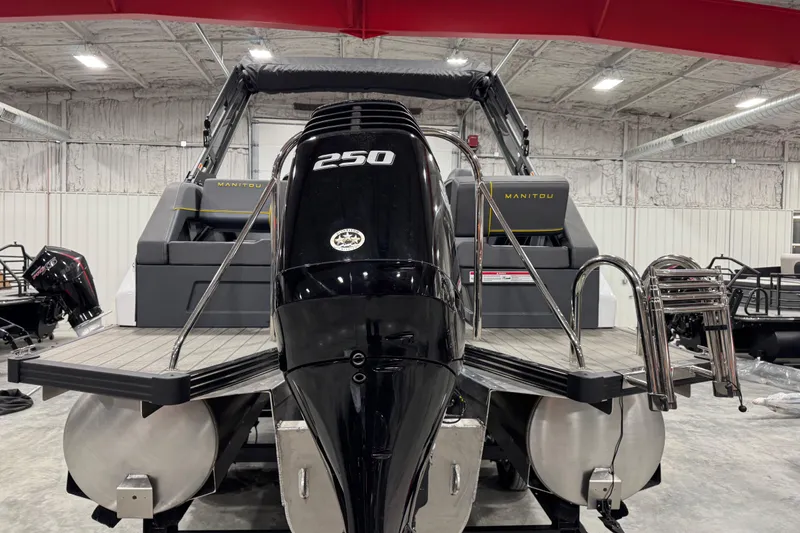 Slide: The Image of 2025 Manitou 24 Explore pontoon boat with powerful 250 HP engine in a showroom. - 6