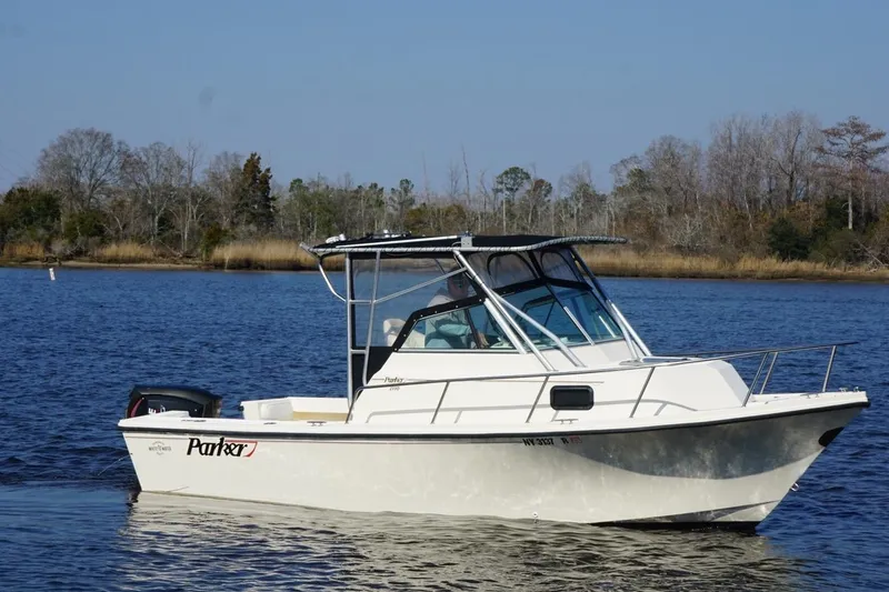 Slide: The Image of 1996 Parker 2110 boat on calm water with wooded shoreline background. - 10