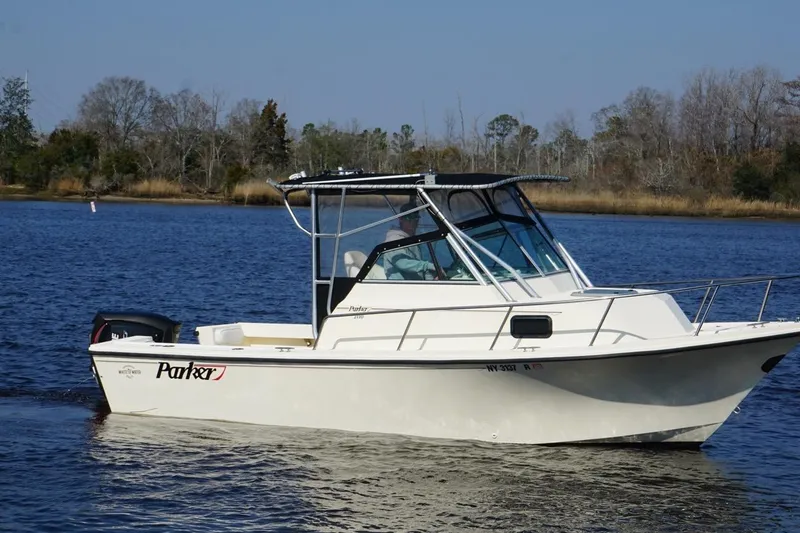 Slide: The Image of 1996 Parker 2110 boat cruising on a calm lake with a wooded shoreline. - 3