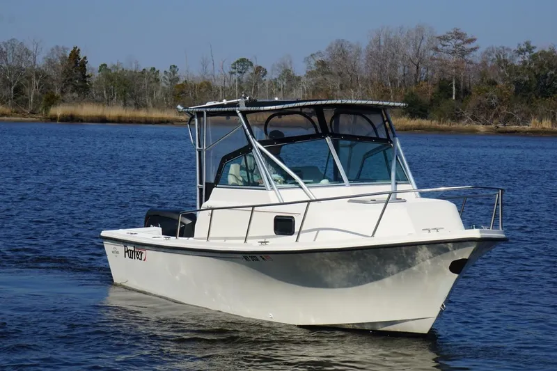 Slide: The Image of 1996 Parker 2110 boat cruising on a calm lake with wooded shoreline. - 4
