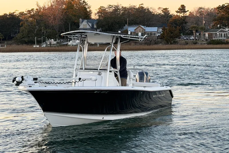 Slide: The Image of 2014 Sea Hunt Ultra 211 boat on calm water near shoreline at sunset. - 11