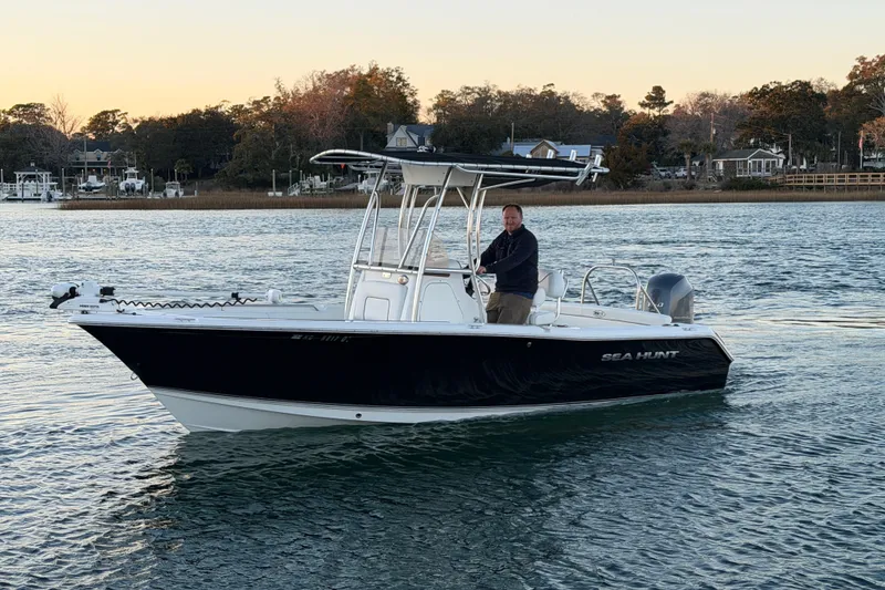Slide: The Image of 2014 Sea Hunt Ultra 211 boat on water at sunset with a person steering. - 13