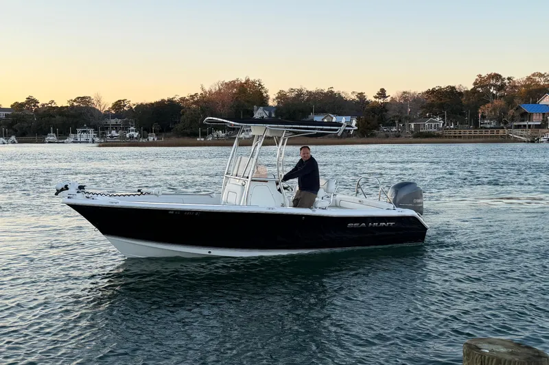 Slide: The Image of 2014 Sea Hunt Ultra 211 boat on water at sunset, with person steering. - 14