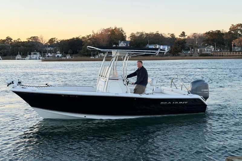 Slide: The Image of 2014 Sea Hunt Ultra 211 boat on water at sunset, with a person steering. - 15