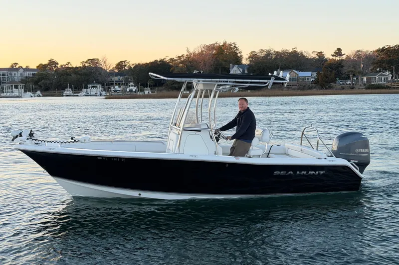 Slide: The Image of 2014 Sea Hunt Ultra 211 boat on water with a person at the helm. - 16