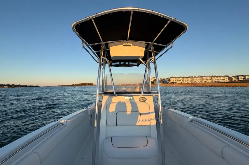 Slide: The Image of 2014 Sea Hunt Ultra 211 boat on calm water at sunset, with coastal buildings in view. - 37