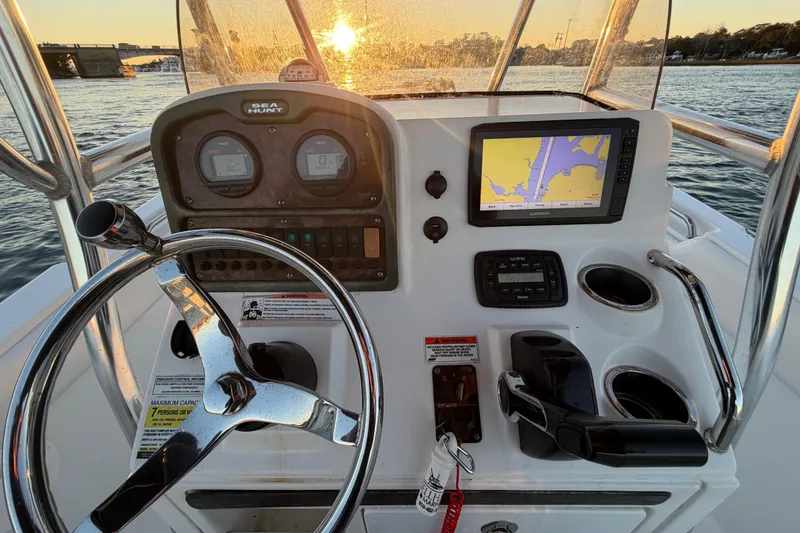 Slide: The Image of 2014 Sea Hunt Ultra 211 boat dashboard with steering wheel, GPS, and sunset view. - 42