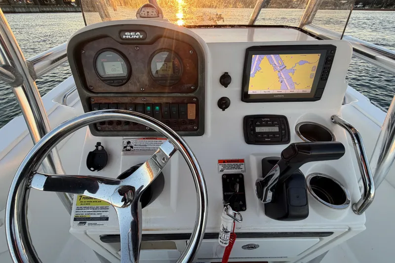Slide: The Image of 2014 Sea Hunt Ultra 211 boat dashboard with steering wheel, gauges, and navigation system at sunset. - 55