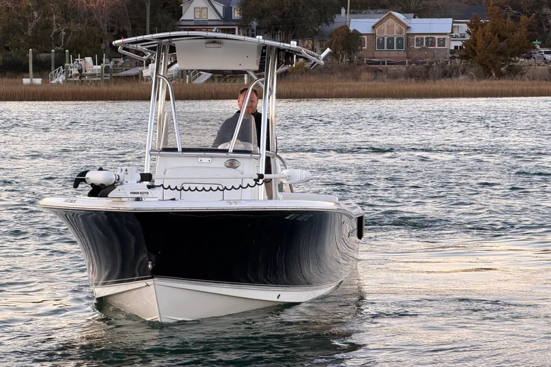 Slide: The Image of 2014 Sea Hunt Ultra 211 boat on water, with person steering near shoreline. - 8