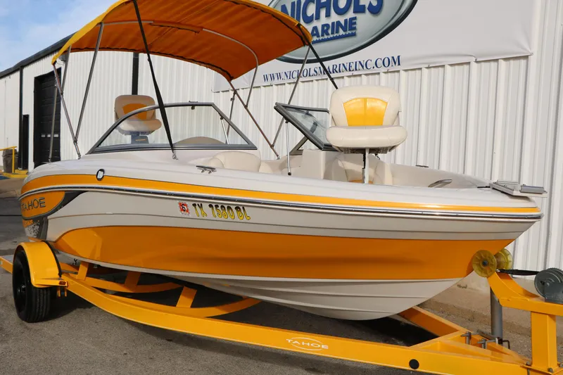 Slide: The Image of 2010 Tahoe Q5i SF boat with yellow accents on a trailer, parked outside a marine shop. - 4