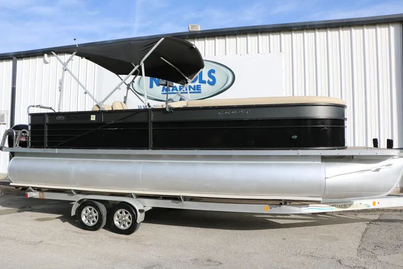 The Image of 2016 Crest II 250 pontoon boat on trailer, black exterior, parked outside marine shop. - 1