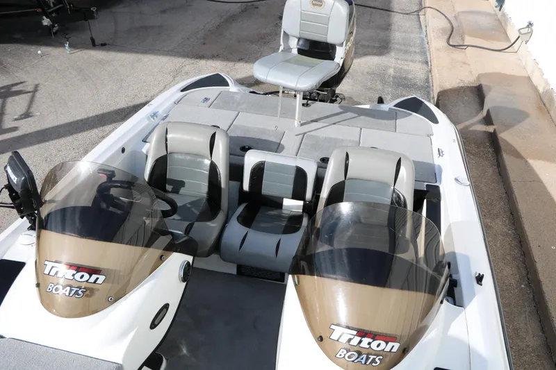 Slide: The Image of 2009 Triton 18 Explorer boat with dual consoles and seating, parked on pavement. - 14