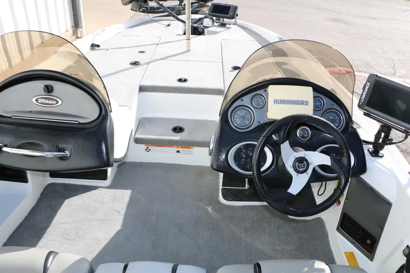 Slide: The Image of 2009 Triton 18 Explorer boat dashboard with steering wheel and Humminbird electronics. - 21