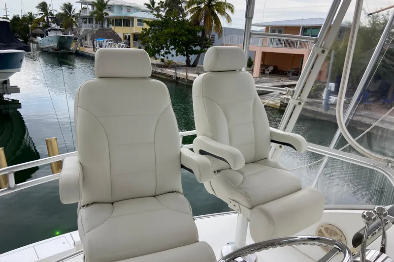 Slide: The Image of Captain's chairs on 2001 Egg Harbor 37 Convertible yacht, docked by waterfront homes. - 52