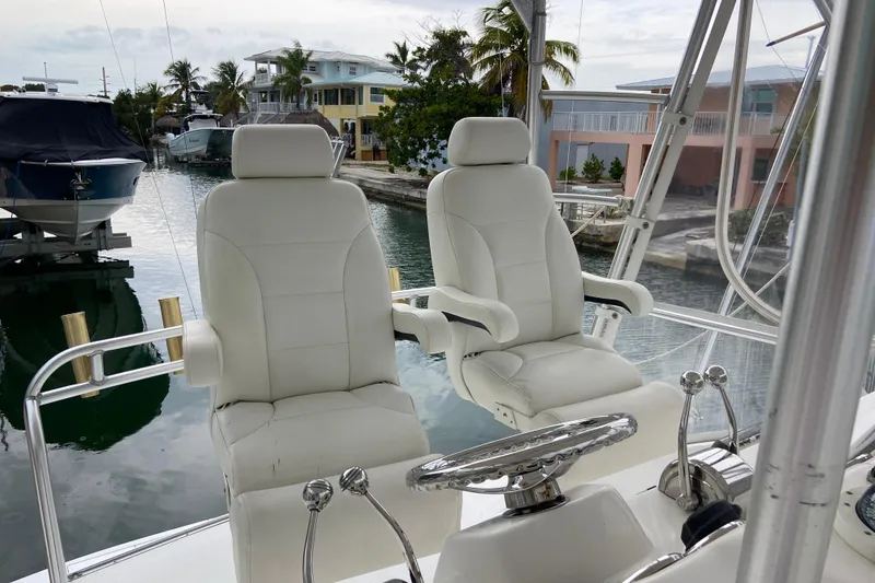 Slide: The Image of Luxury helm seats on a 2001 Egg Harbor 37 Convertible yacht, docked near waterfront homes. - 62