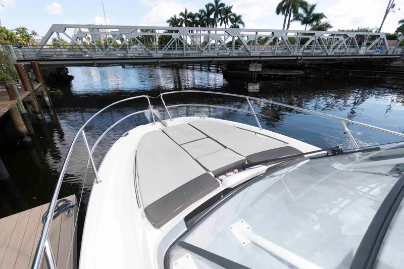 Slide: The Image of 2019 Jeanneau Leader 10.5 boat docked near a bridge, surrounded by water and palm trees. - 12