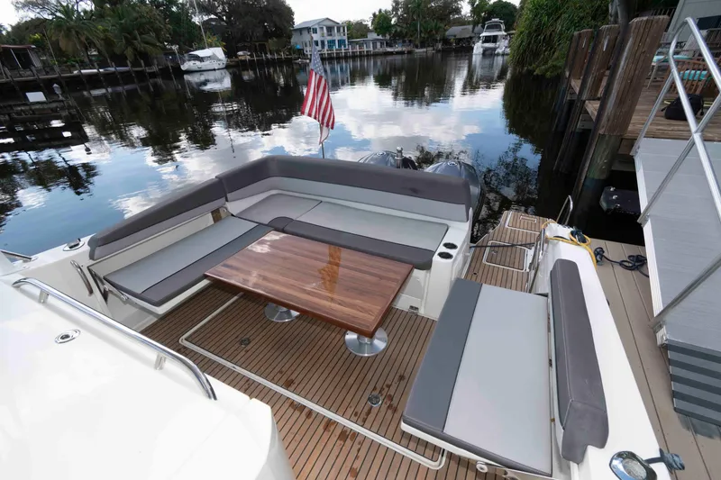 Slide: The Image of 2019 Jeanneau Leader 10.5 boat with elegant seating and wooden table on a serene waterfront. - 2