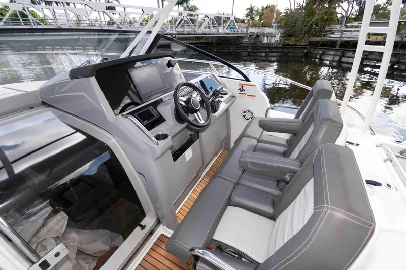 Slide: The Image of 2019 Jeanneau Leader 10.5 cockpit with modern helm, luxurious seating, and scenic waterway view. - 9