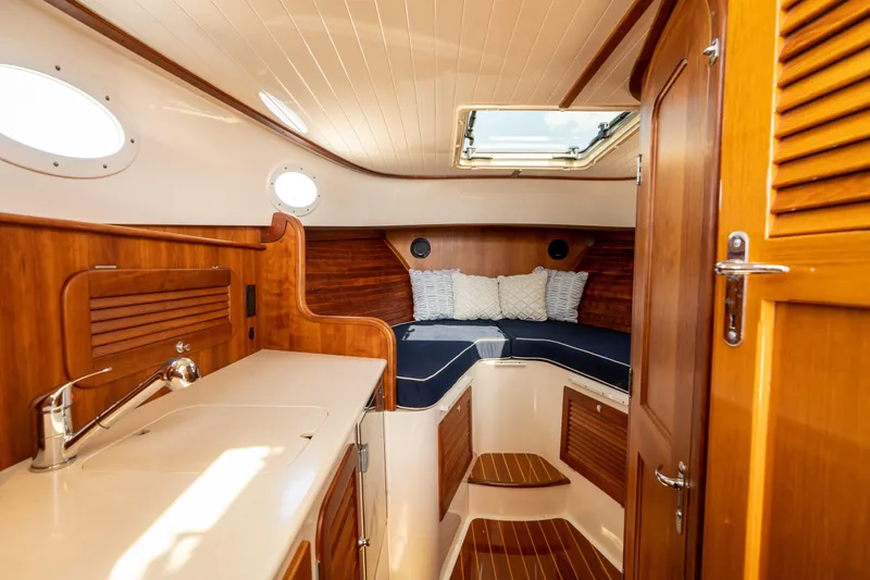 Slide: The Image of 2013 Hinckley Talaria 34 interior with wood finish, cozy seating, and skylight. - 13