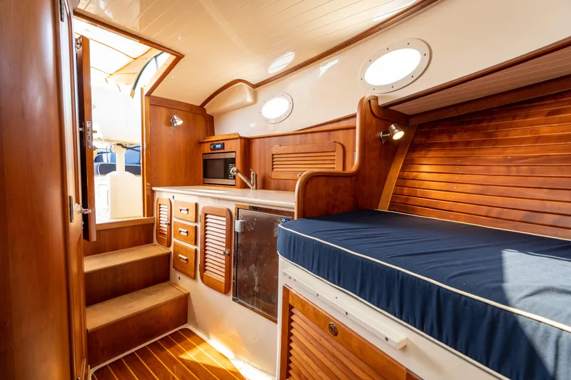Slide: The Image of Interior of 2013 Hinckley Talaria 34 yacht with wooden cabinetry and blue cushioned seating. - 14