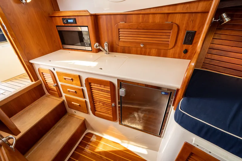 Slide: The Image of 2013 Hinckley Talaria 34 yacht interior with wooden cabinetry and compact kitchen area. - 15