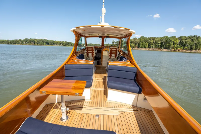 Slide: The Image of 2013 Hinckley Talaria 34 yacht with elegant wooden deck and blue seating on a serene lake. - 4