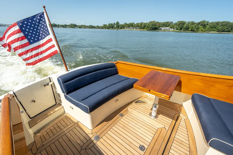 Slide: The Image of 2013 Hinckley Talaria 34 boat with American flag, wooden deck, and blue seating. - 6
