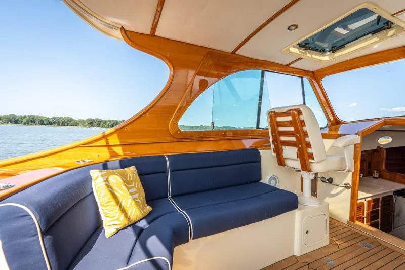 Slide: The Image of 2013 Hinckley Talaria 34 interior with blue seating, wooden accents, and lake view. - 8