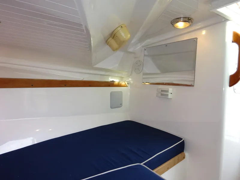 Slide: The Image of 2008 Hunt Yachts Harrier 25 cabin interior with blue cushions and wooden accents. - 30