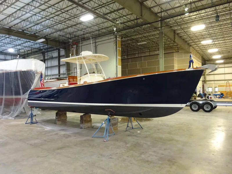 Slide: The Image of 2007 Hinckley T29C boat in a warehouse, elevated on stands, with a sleek navy hull. - 11