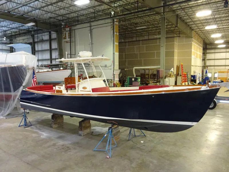 Slide: The Image of 2007 Hinckley T29C boat in a warehouse, elevated on stands, with a sleek navy hull. - 7