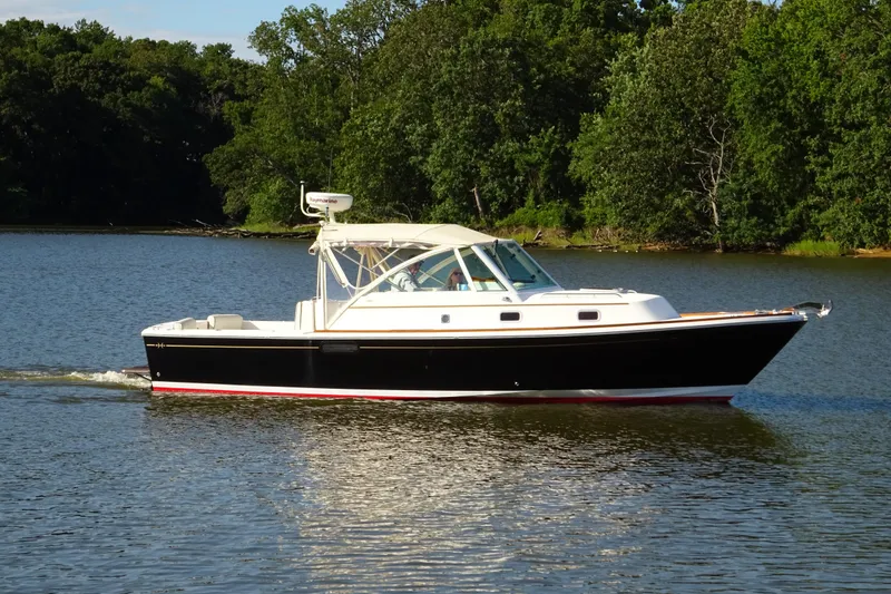 The Image of 2007 Hunt Yachts Surfhunter 29 cruising on a serene lake with lush green trees. - 0