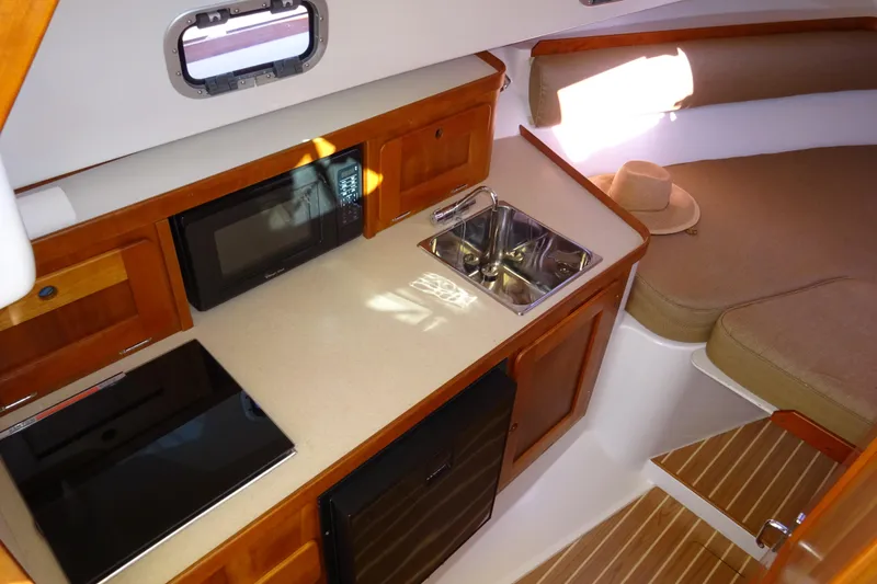 Slide: The Image of 2007 Hunt Yachts Surfhunter 29 interior with kitchenette, sink, microwave, and cozy seating area. - 42