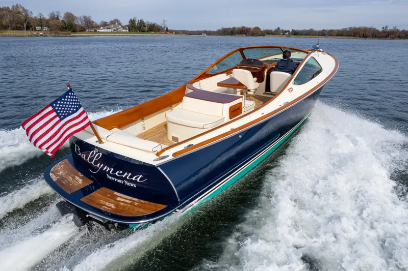 Slide: The Image of 2006 Hinckley Talaria 29 R boat cruising on a lake with American flag. - 2