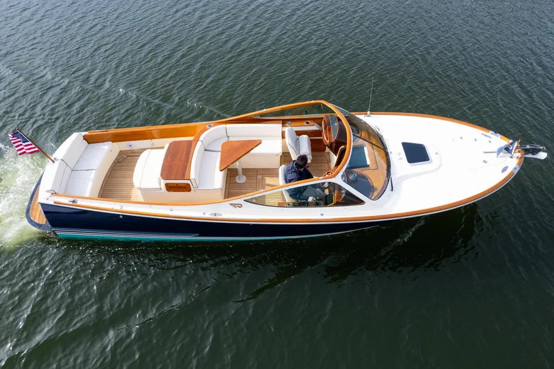 Slide: The Image of 2006 Hinckley Talaria 29 R boat cruising on open water, featuring elegant design and American flag. - 4