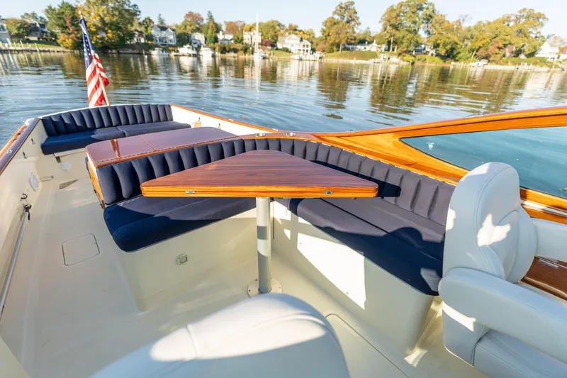 Slide: The Image of 2003 Hinckley Talaria 29 Runabout interior with blue seating and wooden table on calm water. - 12