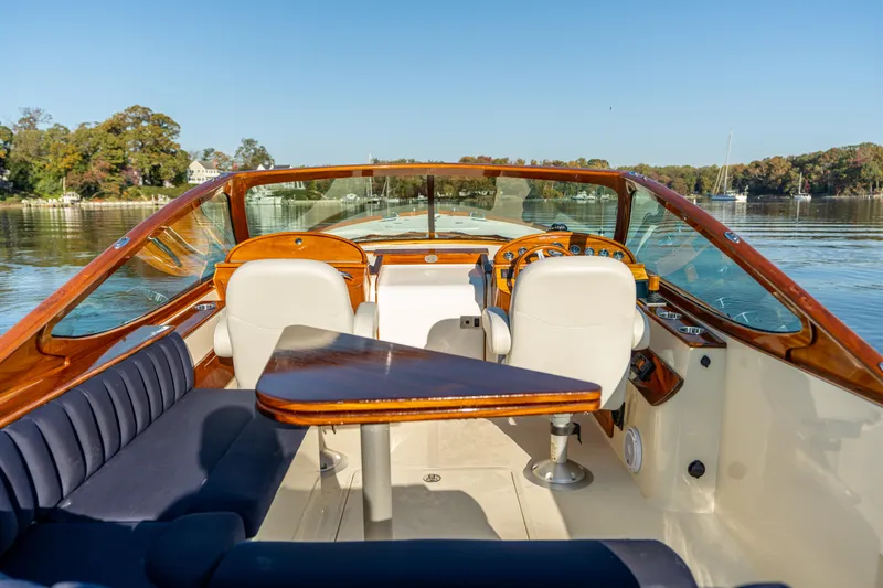 Slide: The Image of 2003 Hinckley Talaria 29 Runabout interior with elegant seating and wooden accents on a calm lake. - 13