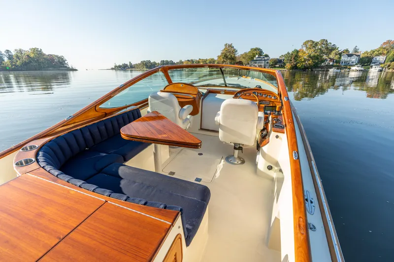 Slide: The Image of 2003 Hinckley Talaria 29 Runabout on calm water, featuring elegant wood and blue seating. - 14