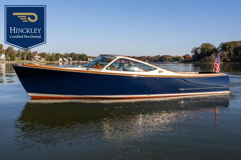 The Image of A sleek blue 2003 Hinckley Talaria 29R glides on calm water. An American flag waves at the stern. - 0