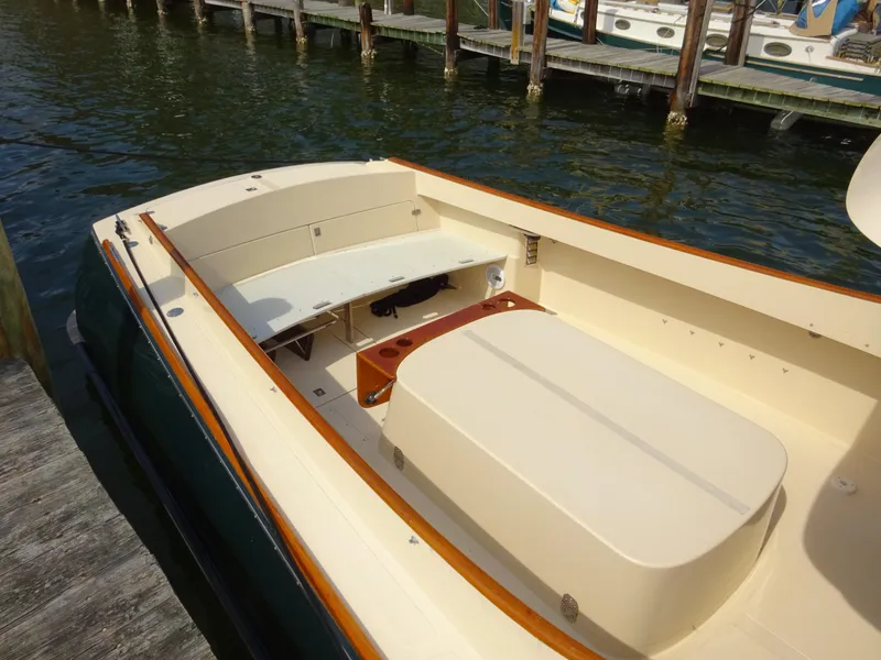 Slide: The Image of 1995 Hinckley Picnic Boat Classic with beige seating and wooden accents docked by the water. - 11