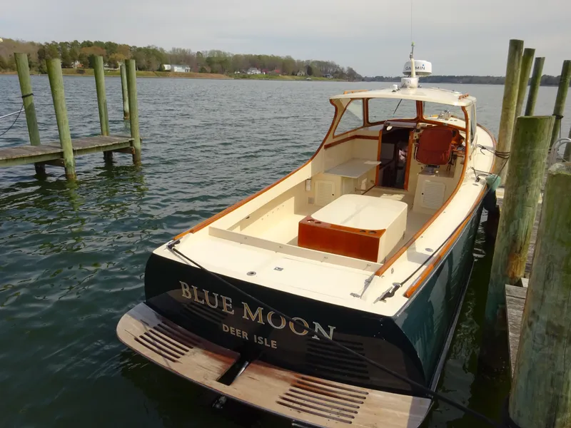 Slide: The Image of Hinckley Picnic Boat Classic 1995, named "Blue Moon," docked at a serene waterfront. - 12