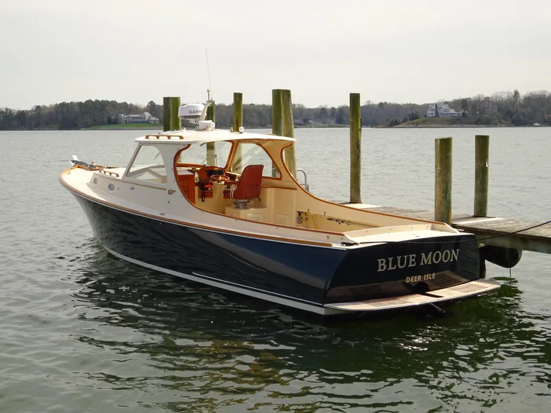Slide: The Image of 1995 Hinckley Picnic Boat Classic docked, named "Blue Moon," with elegant design and serene water backdrop. - 13