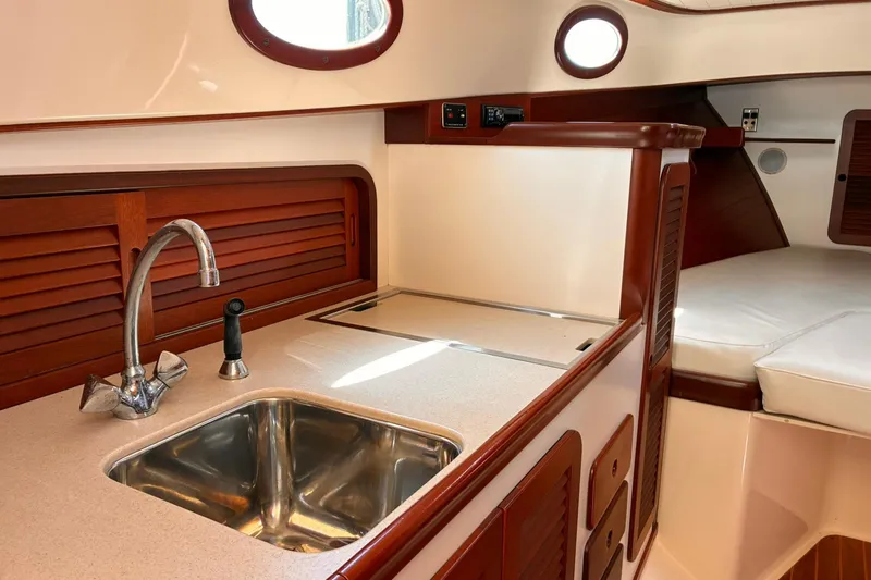 Slide: The Image of Interior of 1995 Hinckley Picnic Boat 36 Classic, featuring a compact kitchen area. - 25