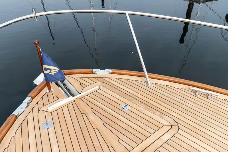 Slide: The Image of Hinckley Talaria 43 (2014) yacht deck with wooden finish and flag, docked on calm water. - 30