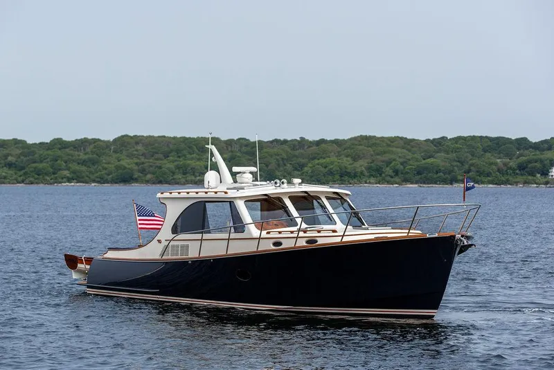 Slide: The Image of 2014 Hinckley Talaria 43 yacht cruising on calm waters with lush green shoreline. - 9