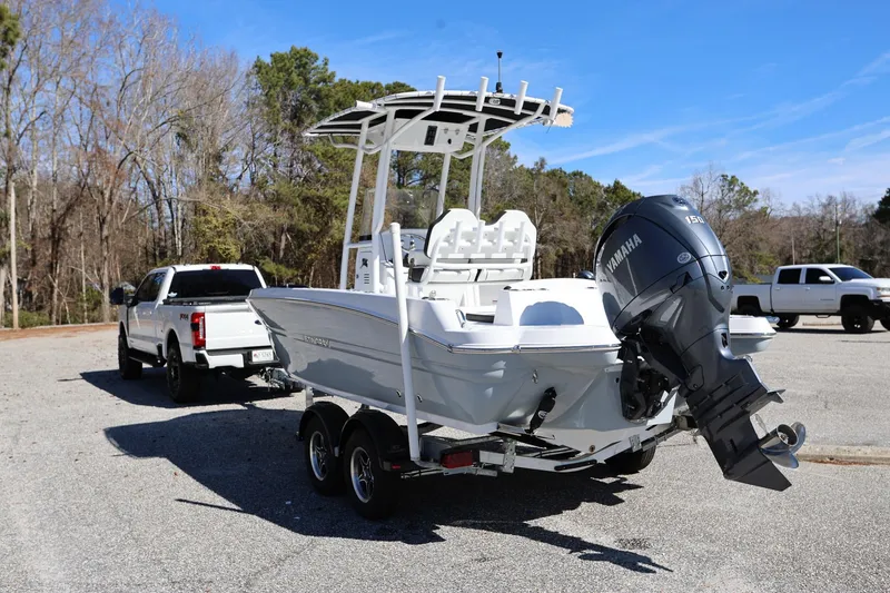 Slide: The Image of 2025 Stingray 216 CC boat on trailer, towed by a white truck in a parking lot. - 3