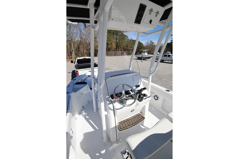 Slide: The Image of 2025 Stingray 216 CC boat interior with steering wheel and seating, parked outdoors. - 8