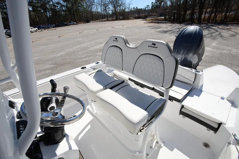 Slide: The Image of 2025 Stingray 216 CC boat interior with steering wheel and cushioned seating. - 10