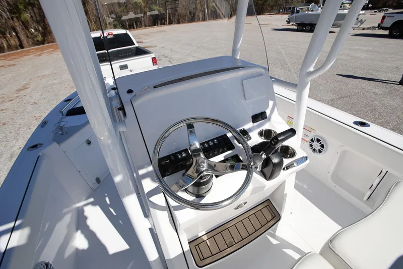 Slide: The Image of 2025 Stingray 216 CC boat console with steering wheel and controls in a parking lot. - 11